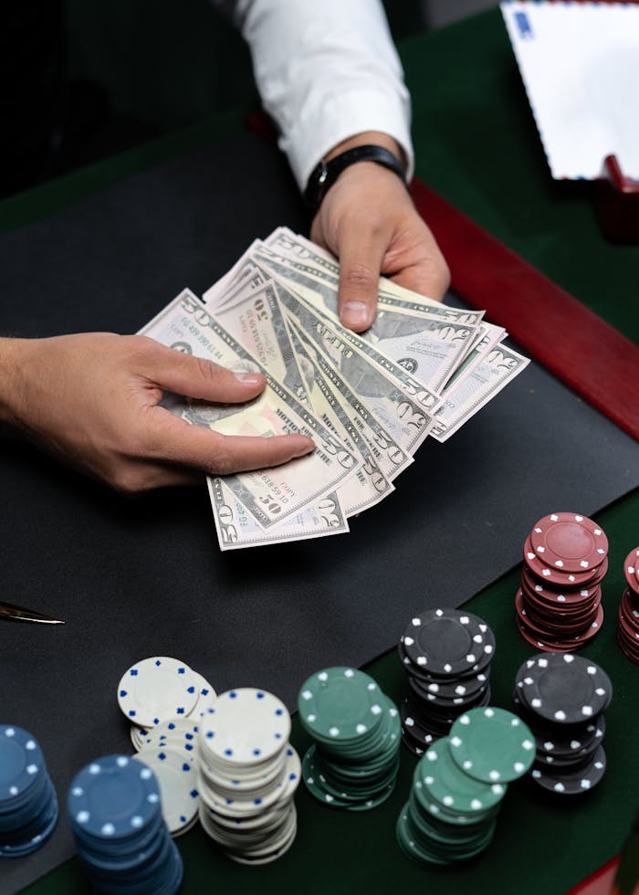 Close-up of hands counting dollar bills on a casino table with poker chips.